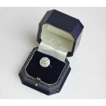 A diamond cluster ring bezel set with a central round stone within eight smaller stones in