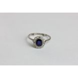 A sapphire and diamond ring the oval cut stone rubover set within a border of eight cut diamonds