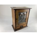 An Art Nouveau oak smokers cabinet with embossed metal panel door of stylised flowers enclosing