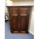 A George III oak hanging corner wall cupboard, with two panel doors enclosing three shaped