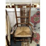 An oak rail back elbow chair with rush seat on turned legs and stretchers