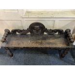 A Victorian carved oak bench with raised scroll back and turned arms, shaped frieze on carved