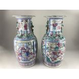 A pair of Chinese porcelain famile rose vases, decorated with panels of figures amongst flowers