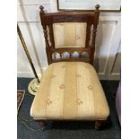 An Edwardian low chair with carved floral back and turned supports, upholstered back panel and