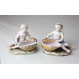 A pair of Meissen porcelain figural salts, the figures seated before shells, 11cm high