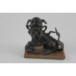 A Chinese bronzed metal model of a Dog of Fo, mounted on rectandular wooden base, 13cm high