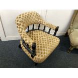 A Victorian ebonised tub chair with upholstered raised back on turned supports, turned legs and
