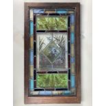 A pair of wooden framed stained glass windows, the leaded panels decorated with the profile of a