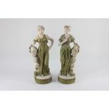 A pair of Royal Dux porcelain figures of female water carriers beside urns on naturalistic bases,