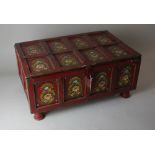 A red painted box with hinged lid, possibly Indian, the top and sides decorated with floral