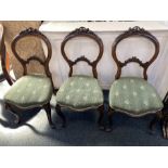 A set of three Victorian balloon back chairs, each with carved surmount, splat and cabriole legs