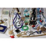 A collection of costume jewellery to include beaded necklaces and brooches, pendants, a Napier