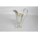 An Edward VII silver cream jug helmet form with loop handle on square pedestal base, makers D and