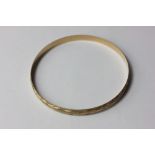 A 9ct gold bangle with engraved and textured decoration