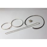 A silver open end torc necklace; two silver bangles; a silver crown brooch