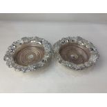 A pair of silver plated bottle coasters, with embossed grapevine design