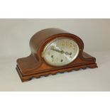 An Edwardian mahogany mantle clock, with oval dial and arch shaped case, striking on chimes, 20cm