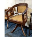 An Edwardian office chair with open arms and slatted supports, later rattan panel back and seat,
