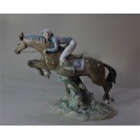 A large Lladro model of a model of a race horse and jockey vaulting a fence, 33cm high