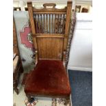 An Edwardian inlaid oak nursing chair with spindle and panelled back (a/f), upholstered seat on