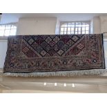 A large Eastern carpet, blue ground, decorated with stylized floral motifs surrounded by a border,
