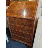A small yew wood veneered bureau, with drop flap enclosing interior of pigeon holes and drawer,