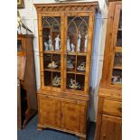 A yew wood veneered bookcase, with two glazed panel doors enclosing three adjustable shelves,