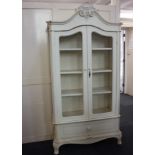 A modern cream painted armoire, with two mesh panel doors enclosing three shelves, drawer below,