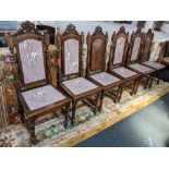 A set of six Carolean style oak high back dining chairs, with scroll carved crests and turned