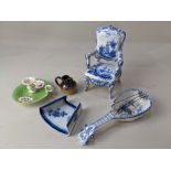 A Delft blue and white miniature model of an armchair, decorated with views of boats and a figure in