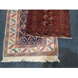 A 'Bokhara' pattern rug, rust coloured ground with single row elephant feet surrounded by border,