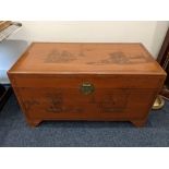 A Chinese carved camphor wood blanket chest, decorated with sailing ships and figural scenes, on