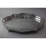 A silver plated serving tray with serpentine shaped pierced raised border and scroll and foliate