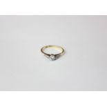 A diamond single stone ring claw set with small side stones in 18ct gold and platinum