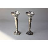 A pair of George V silver vases with pierced rims on tapered stems and loaded circular bases, (af)