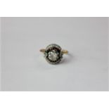 A circular white stone cluster ring on 18ct white gold with claw set centre stone in pierced border