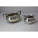 A George V silver matching silver sugar bowl and cream jug rectangular form with gadrooned