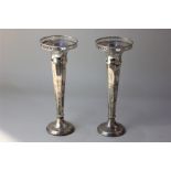 A pair of George V silver vases with pierced rims on facetted tapered stems and loaded circular