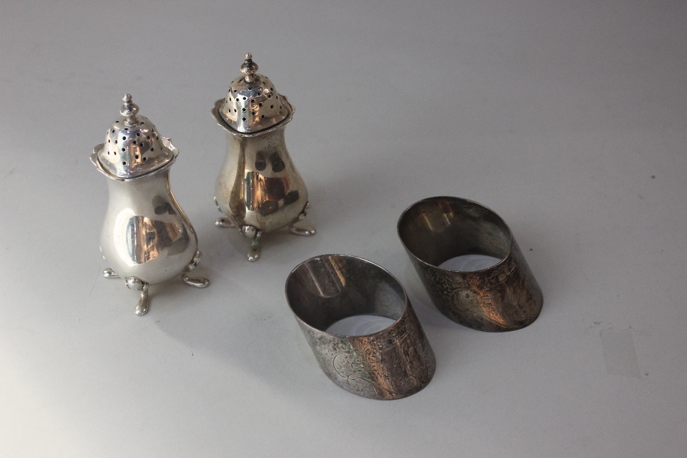 A pair of George V silver pepper pots baluster shape on four hoof feet, maker Elkington and Co.,