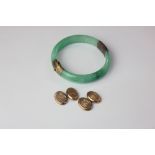 A yellow metal mounted jade bangle with two hinged sections united by a hinge and clasp,