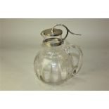 A Victorian silver mounted glass claret jug, facetted globe form with silver lid and scroll