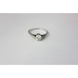 A diamond single stone ring, six claw set with a brilliant cut stone and with three small shoulder