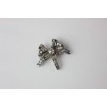 A late 19th / early 20th century diamond set ribbon brooch with central set stone surrounded by