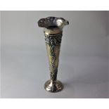 A late Victorian silver trumpet shape vase with embossed scrolls and flowers and circular base,