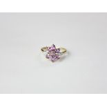 A 9ct gold purple sapphire flower shaped ring with tiny diamond shoulders