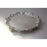 A Victorian silver salver with engraved decoration and shell and scroll pie crust border on four