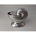A silver plated nautilus shell shaped spoon warmer with hinged lid on floral engraved oval base,