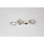 A gold oval shaped open ring with three stones; a silver and paste ring; two gold and gem set rings