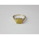 A 9ct gold opal ring with four claw set oval stone