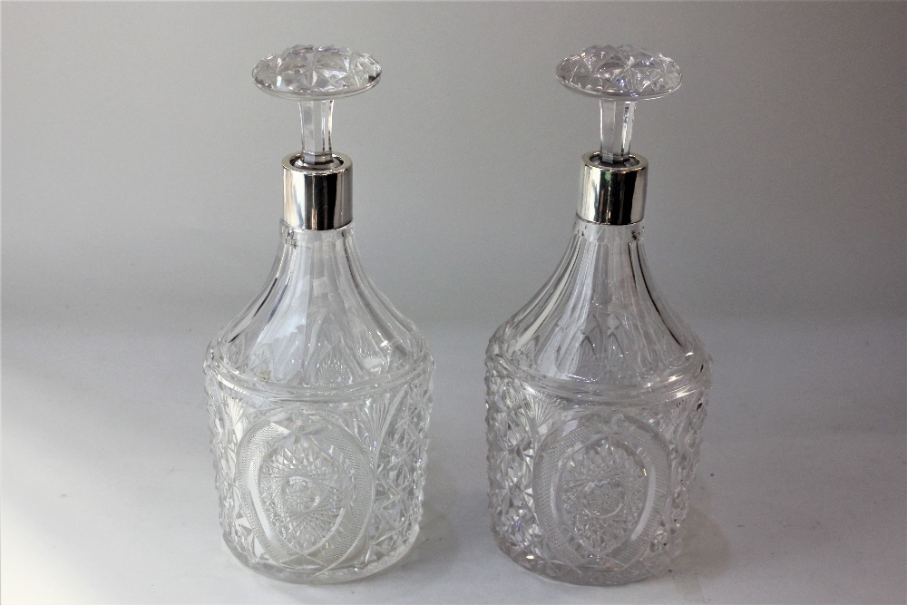 A pair of George V silver mounted cut glass decanters cylindrical shape with tapered necks and